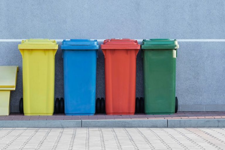 Recycling Bins - four assorted-color trash bins beside gray wall