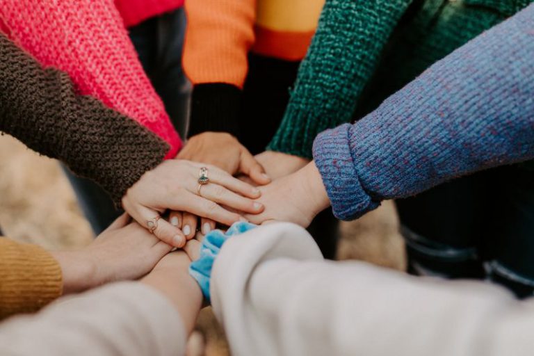 Helping Hand - person in red sweater holding babys hand