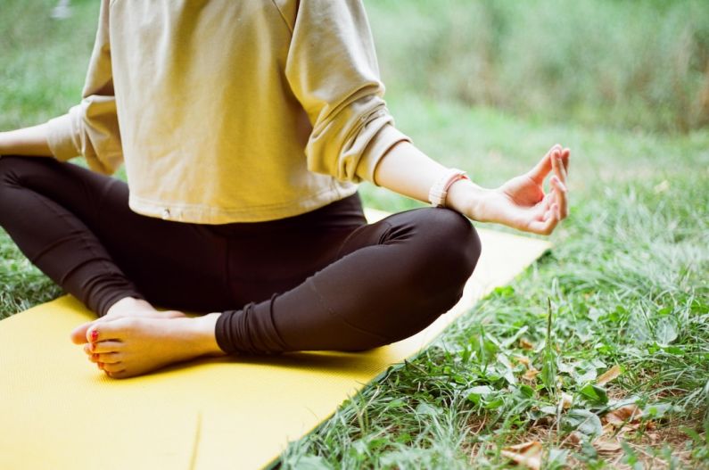 Outdoor Yoga - woman in brown long sleeve shirt and black pants sitting on white textile