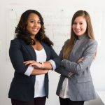 Women Entrepreneurs - two women in suits standing beside wall