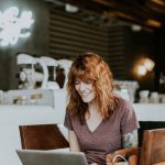 Happy Volunteer - woman sitting on brown wooden chair while using silver laptop computer in room