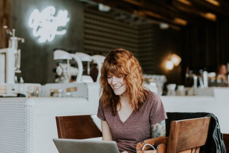 Happy Volunteer - woman sitting on brown wooden chair while using silver laptop computer in room