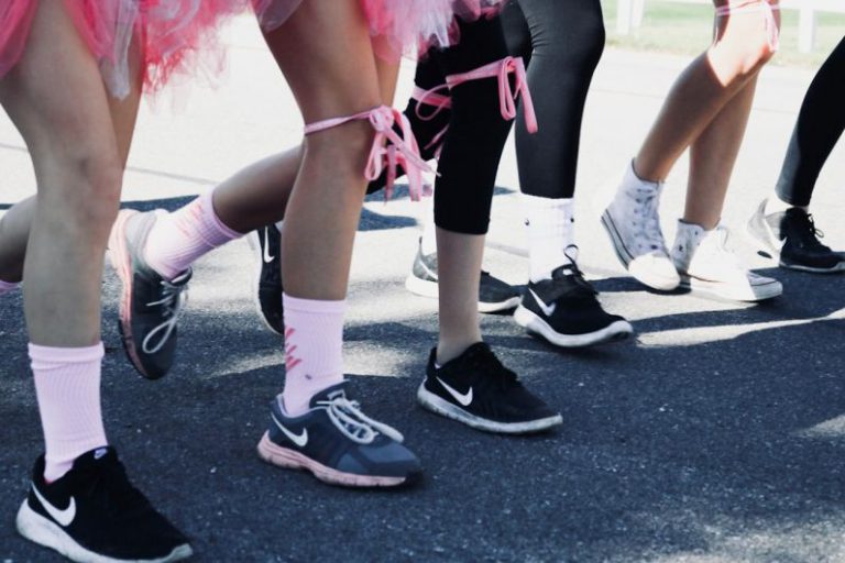 Charity Run - person wearing several pairs of Nike running shoes standing on grey concrete ground during daytime