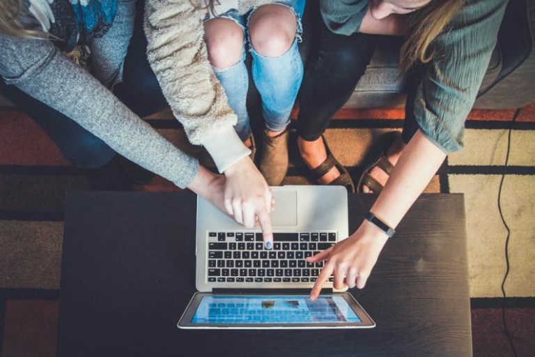 Youth Volunteering - three person pointing the silver laptop computer