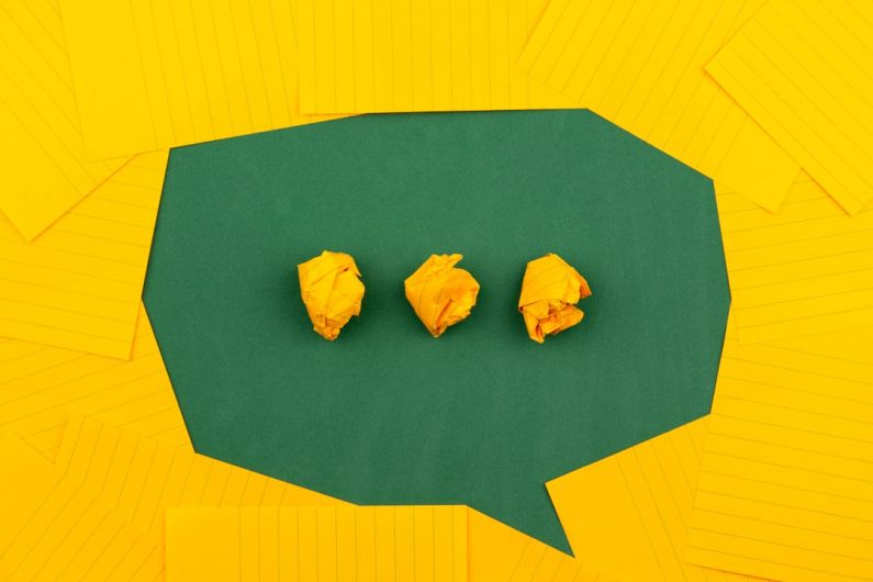 Dialog - three crumpled yellow papers on green surface surrounded by yellow lined papers