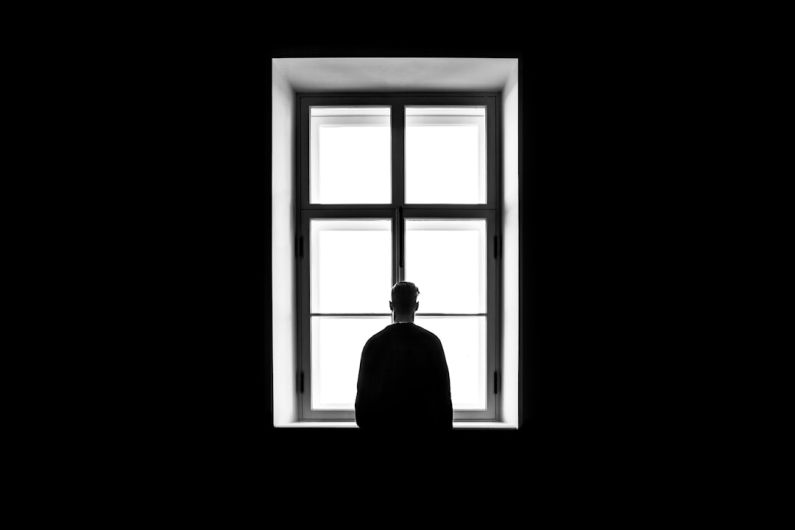 Loneliness - man standing in front of the window