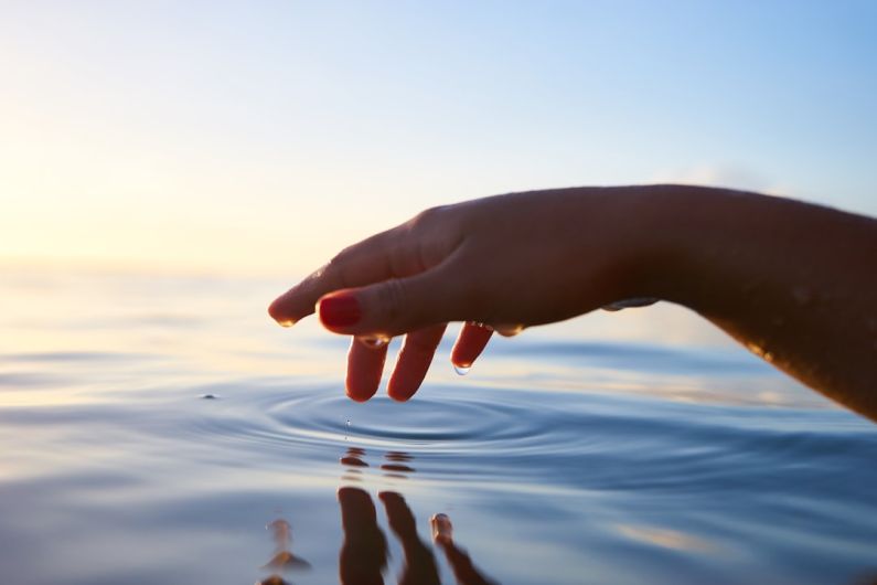 Water Conservation - person about to touch the calm water